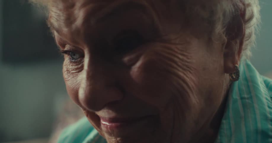 An elderly woman has a sad expression on her face as she leans forward