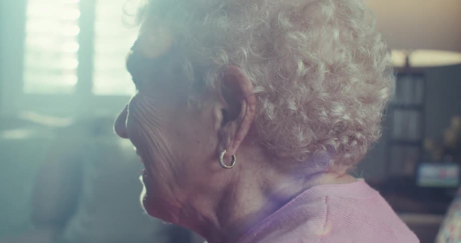 Side portrait of smiling elderly woman with white curly hair