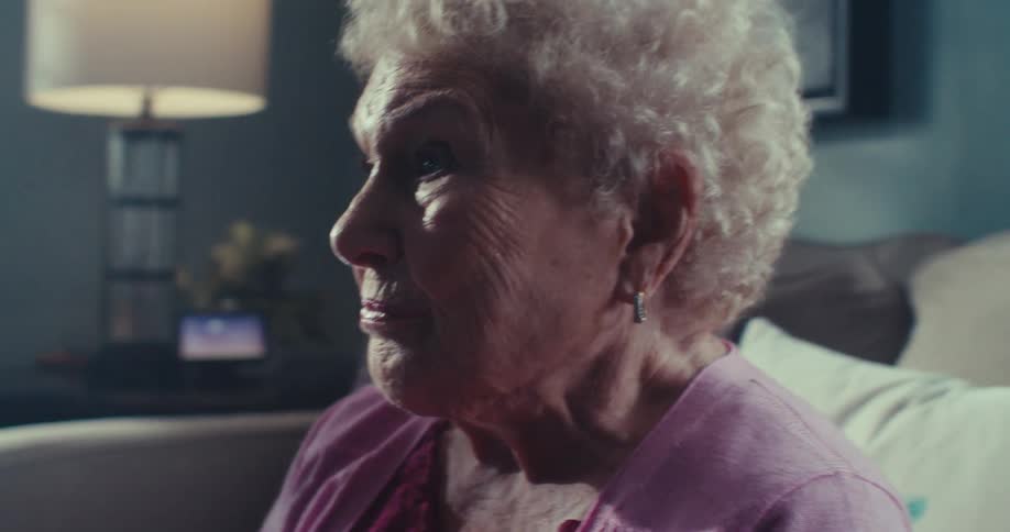Upset elderly woman frowns while sitting in her living room during the daytime