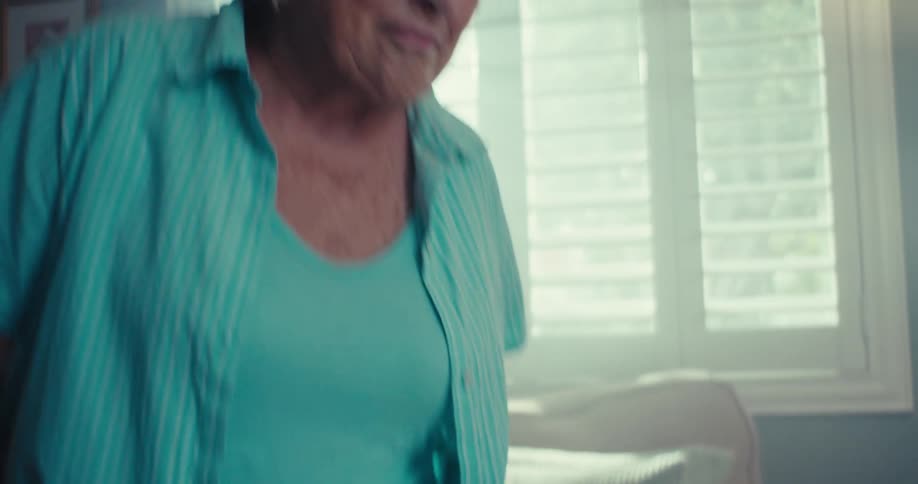 Elderly woman smiles and dances while standing in a living room