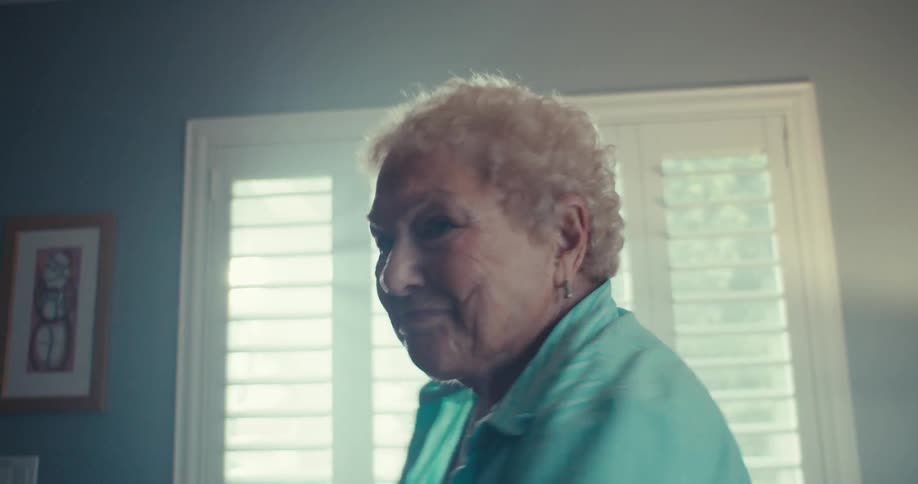 Elderly woman dances in her living room during the daytime