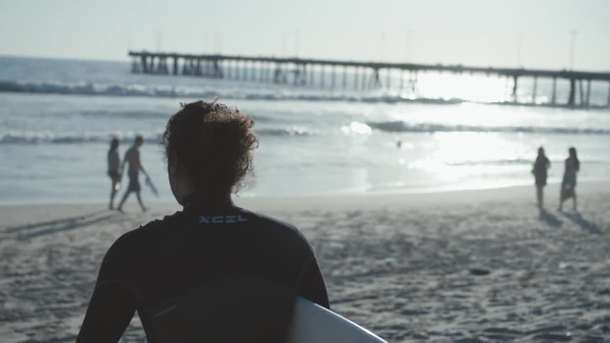 A surfer walks towards the ocean with a surfboard in hand