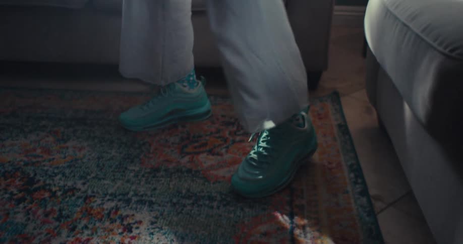 An elderly woman dances in her living room at midday wearing blue sneakers and filled with happiness and excitement
