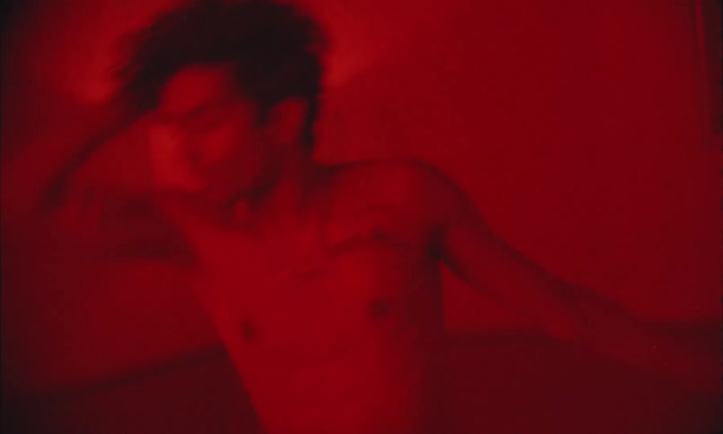 Shirtless man dancing in a red light room