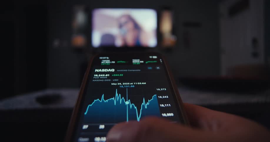 Close up of a person navigating a trading interface on a mobile app while using a phone in the living room