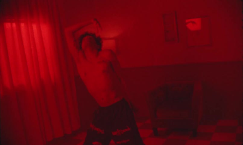 Boy in a room with red lighting dancing without a shirt