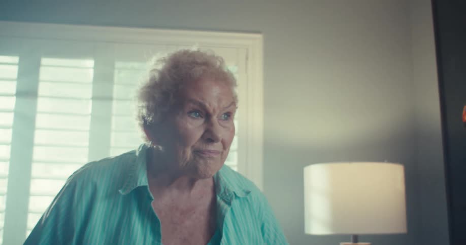 Elderly woman smiles while dancing in her living room during the daytime