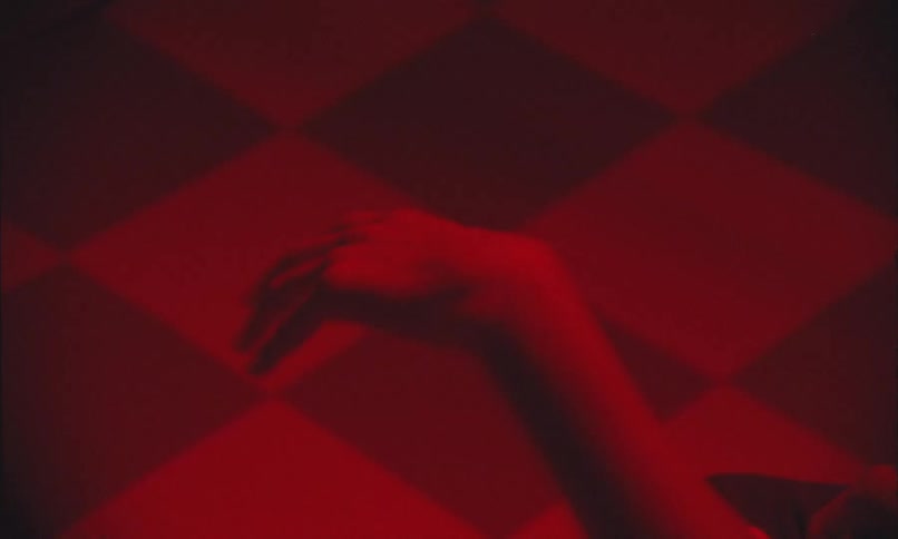 Hand hanging limply in a room lit by red lighting suddenly flips palm up