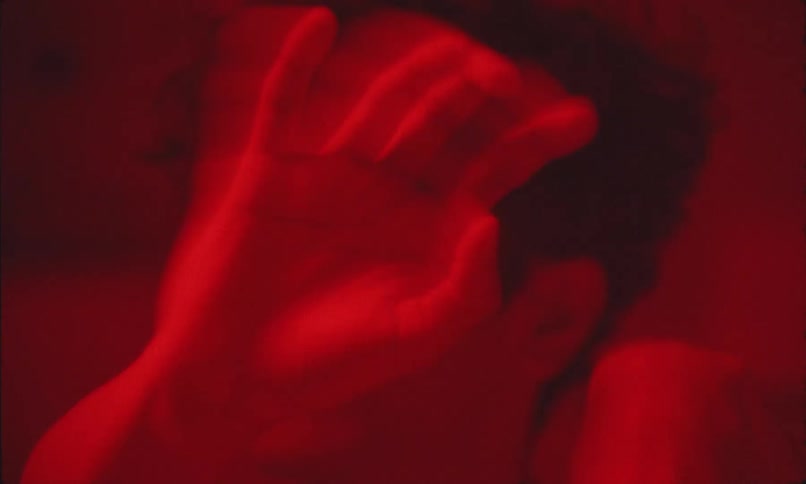 A man looks side to side as his hands wave incredibly fast in front of him