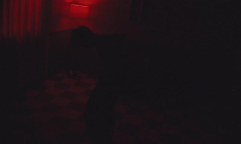 A shirtless boy dancing in a dark room with flickering light