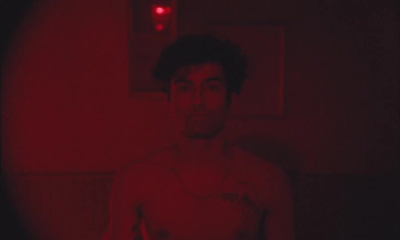 A man is standing alone in a room with flashing red lights