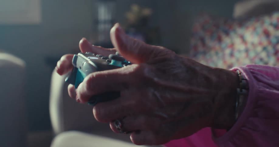 Elderly woman smiles while playing a video game in her living room