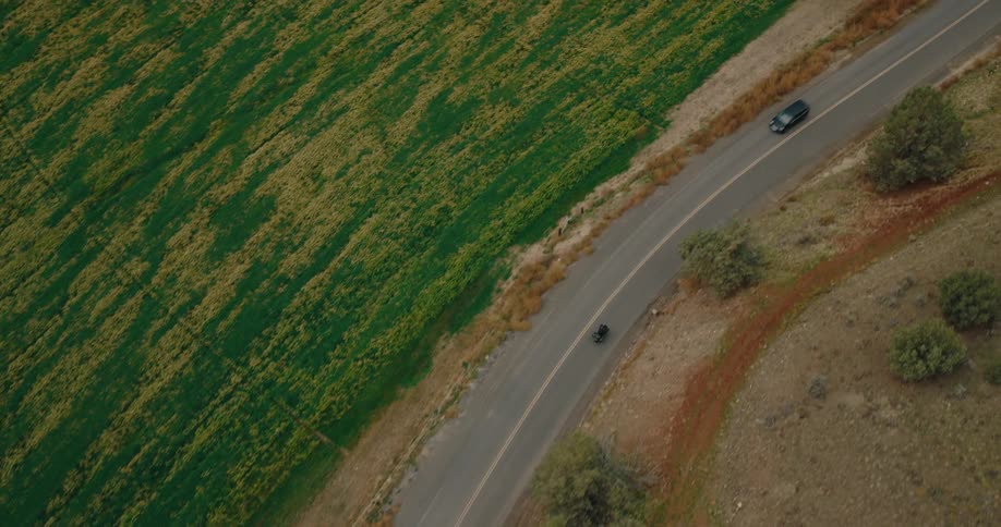 Aerial view of a motorcycle driving down a winding arid country highway