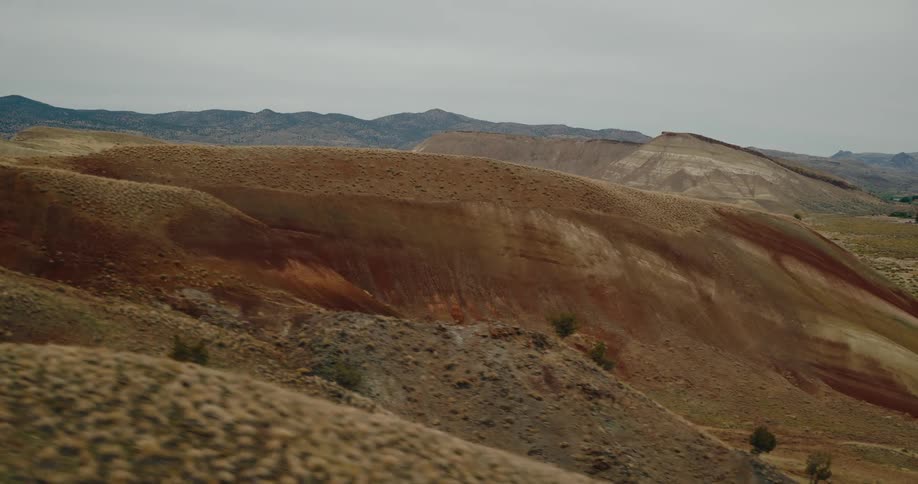 Descending landscape view of rolling desert hills and a gray sky horizon during the day