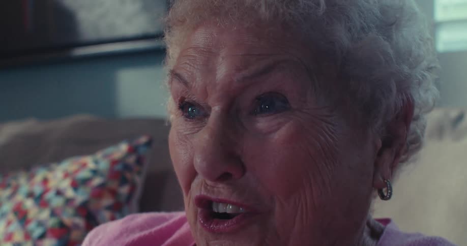 An elderly woman smiles and is having fun as she plays a video game