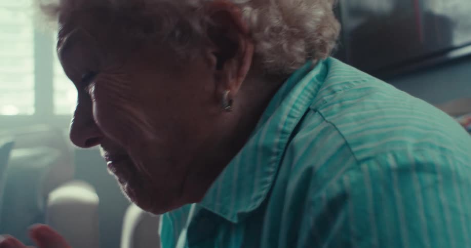 Elderly woman rejoices and celebrates as she views media content on a tablet device while sitting in a living room