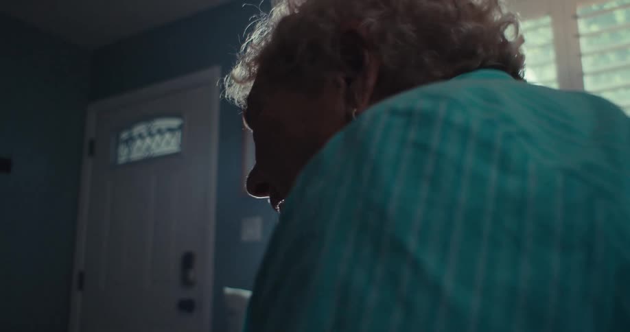 An elderly woman leans forward as she converses via tablet computer
