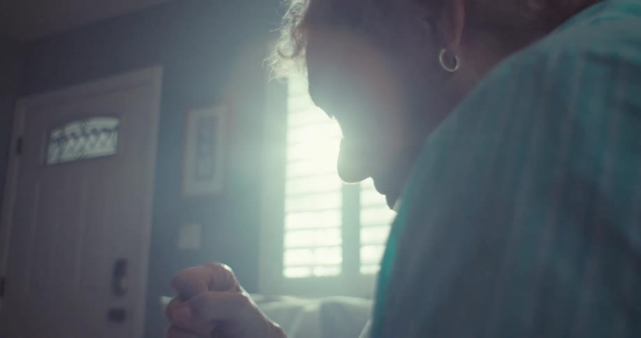 Elderly woman watches her tablet in hopeful excitement while sitting at home during the daytime