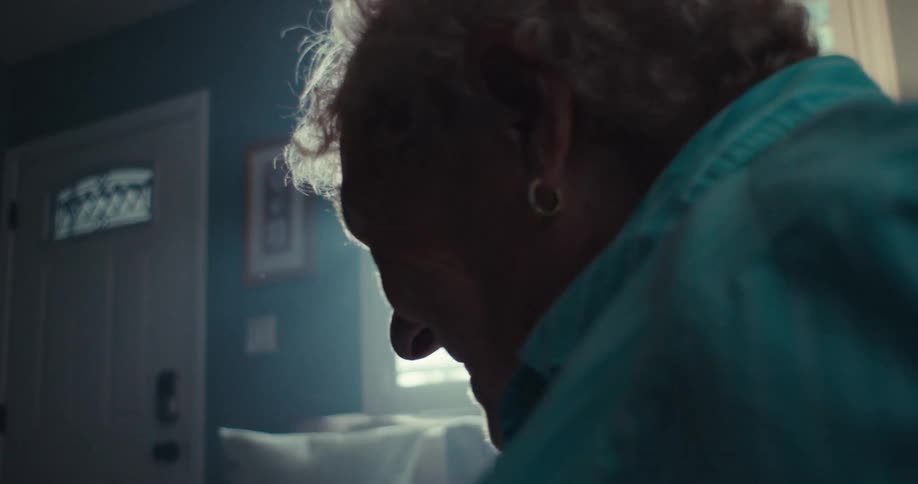 Elderly woman cheers while sitting in her living room and watching her tablet during the daytime