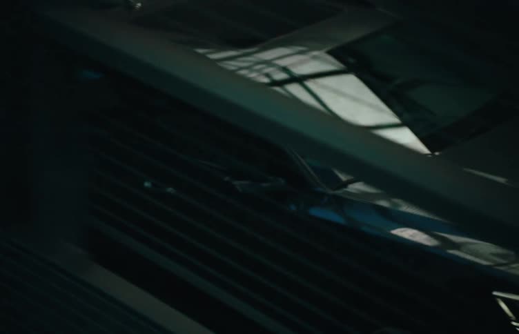 A sedan car drives through a steel bridge at midday