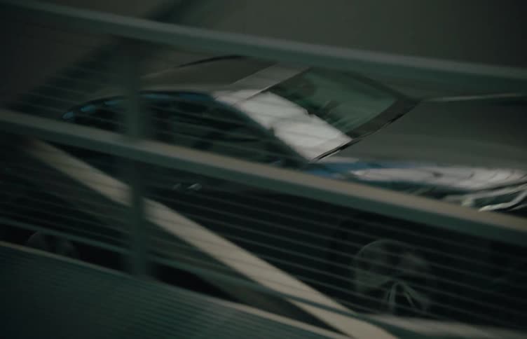 A black car is exiting a parking ramp during the daytime