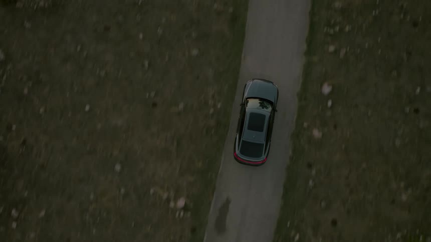 Top view of a car traveling along a narrow road in a natural environment
