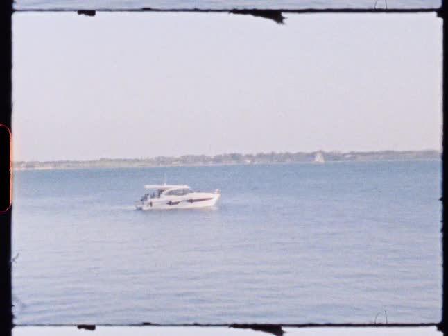 A lone boat floats on a calm body of water under a clear sky