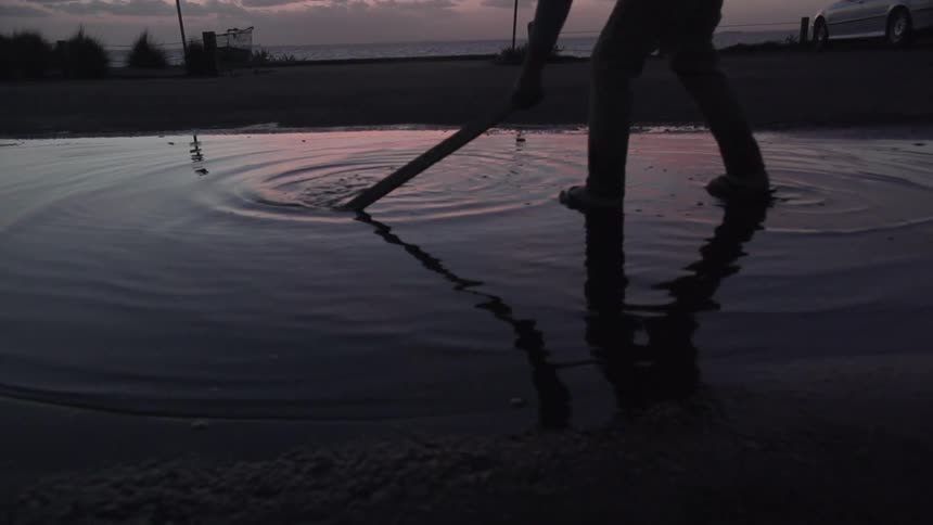 A person is digging around in the water at sunset