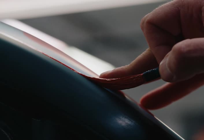 Man with a tattoo on his hand applies paint to a machine