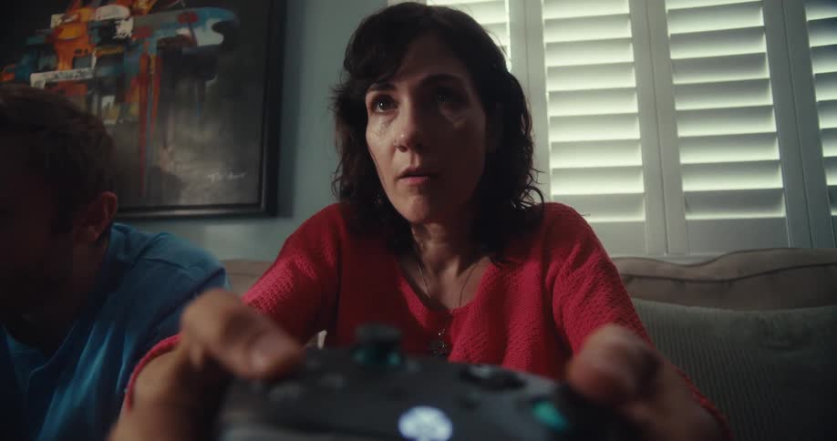 A woman sits on a couch with an expression of intense concentration her hands gripping and operating a video game controller