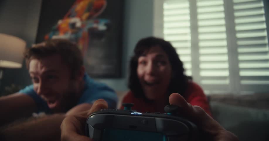 Man and woman play a video game energetically while sitting in the living room during the daytime