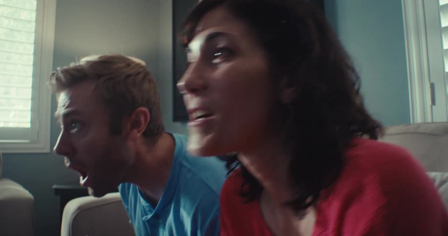 Woman cheers and man frowns while competing during a video game