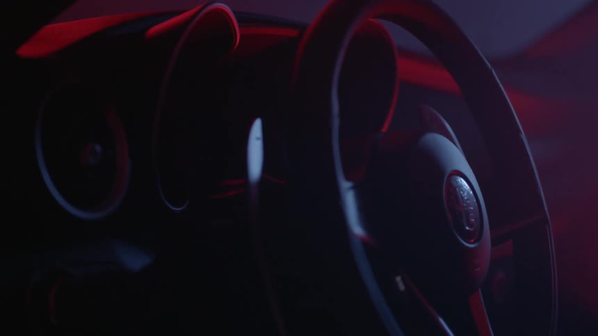 A steering wheel sits still in a dark car