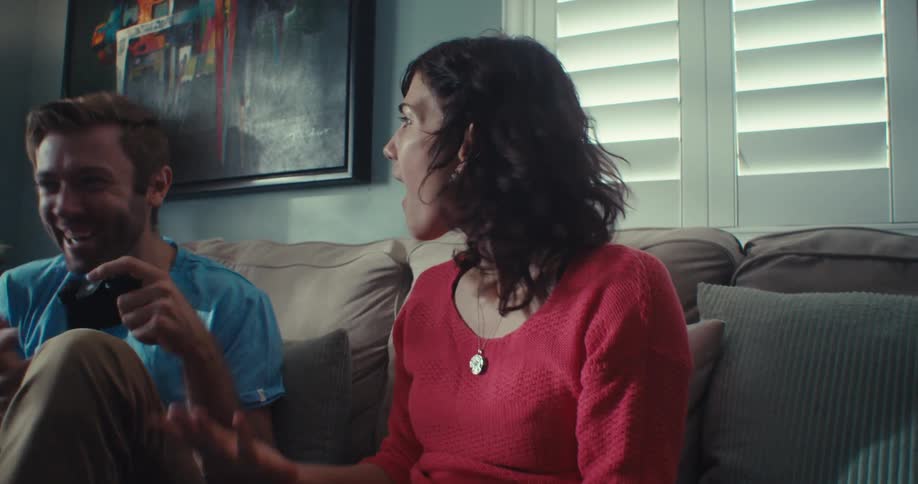 Man and woman sitting on the couch playing video games