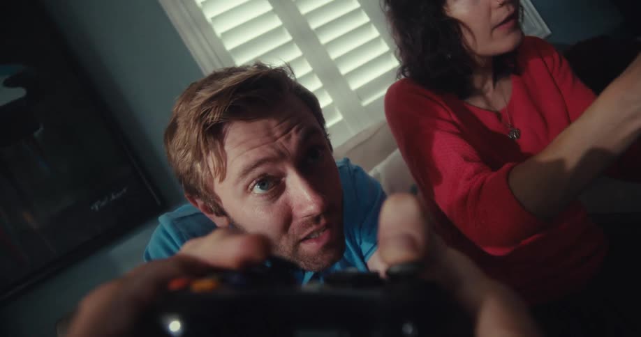 Man and woman focus on manipulating their game controllers while playing a video game at home during the daytime