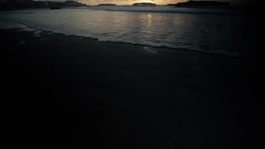 The tide rolls over the sand at sunrise