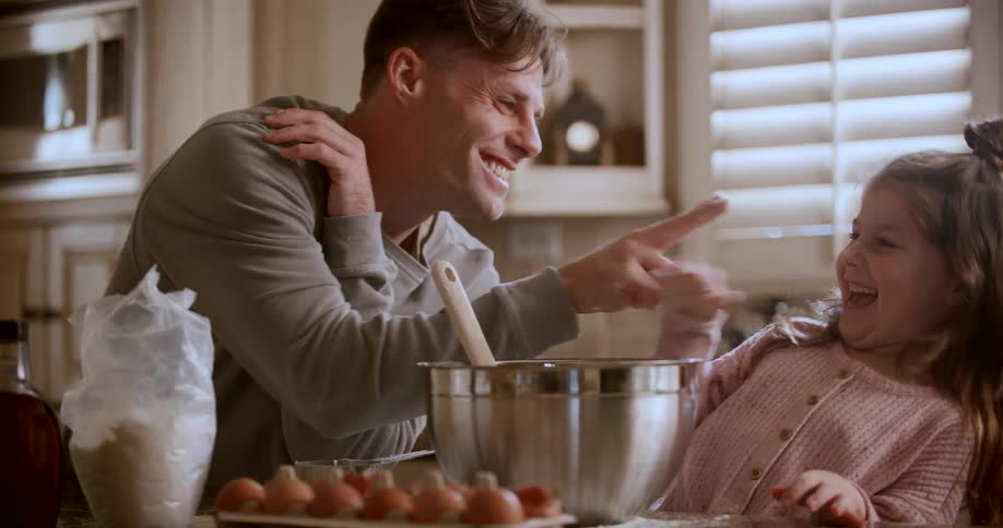 A father and daughter play while they cook