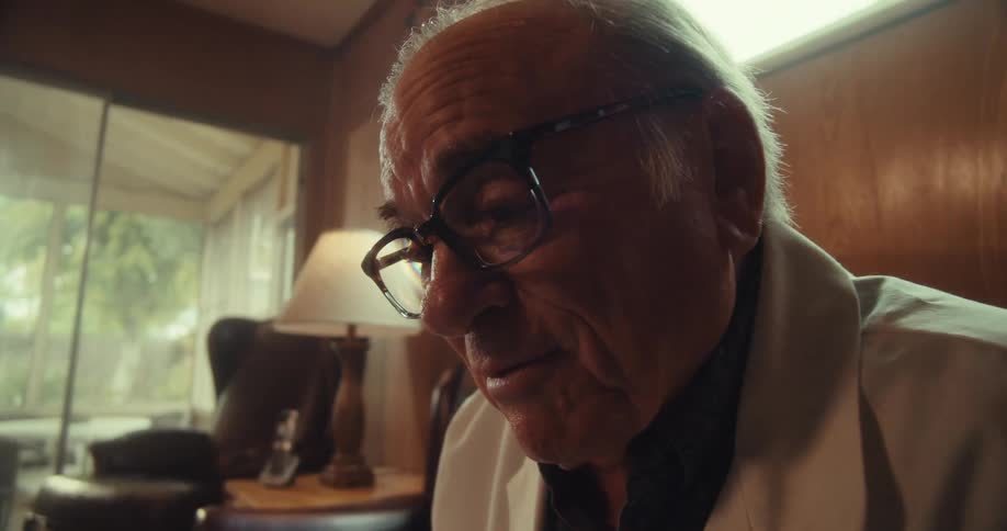 Close up of an elderly male doctor speaking in a virtual consultation while sitting in a living room