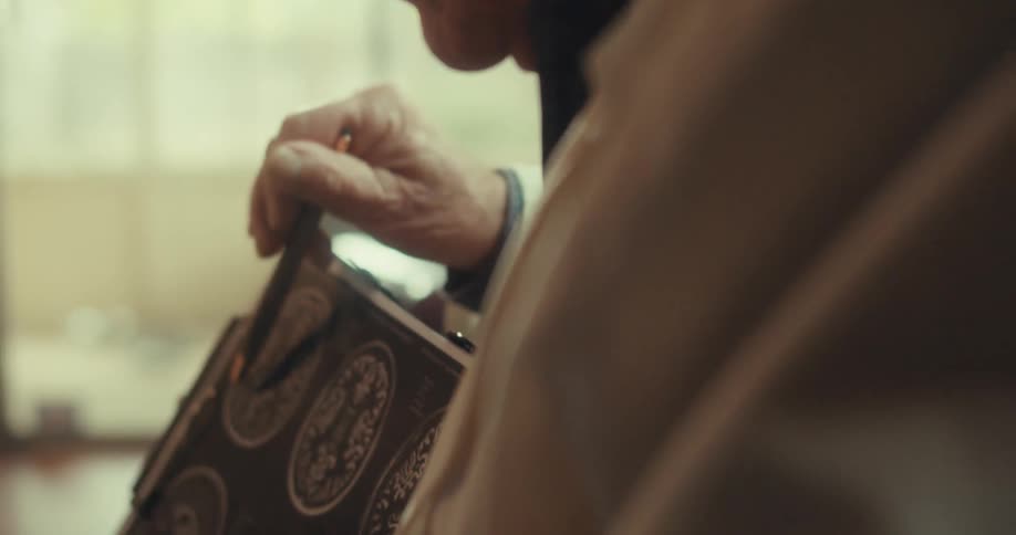 Elderly male doctor wearing a white coat talks while pointing at different brain scan images