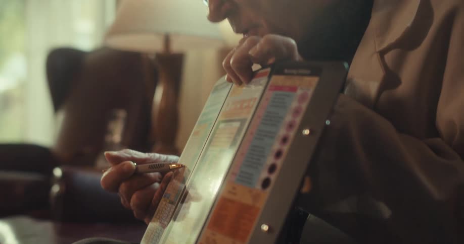 Elderly doctor points to a handheld chart with a pen while in a virtual consultation in a living room