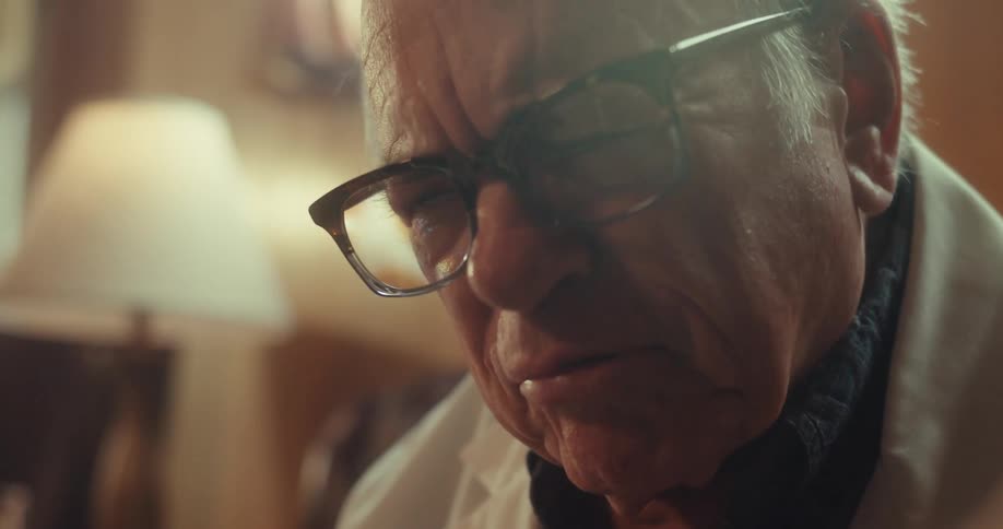 Close up of an elderly doctor pointing to diagrams on a handheld chart as he explains on a virtual consultation while sitting in a living room