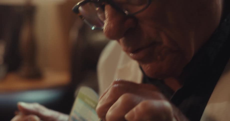 Close up of an elderly male doctor pointing to a chart with a pen while speaking in a virtual consultation