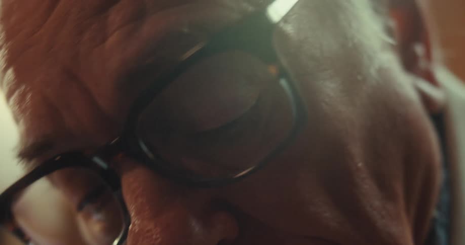 Elderly man wearing glasses and holding a pen showing a panel with text