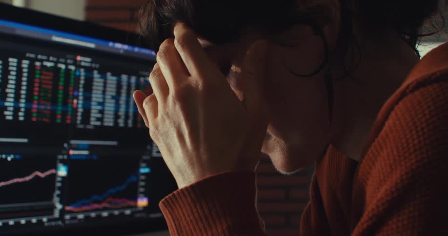 A woman sits in front of a computer screen looking sad and disappointed