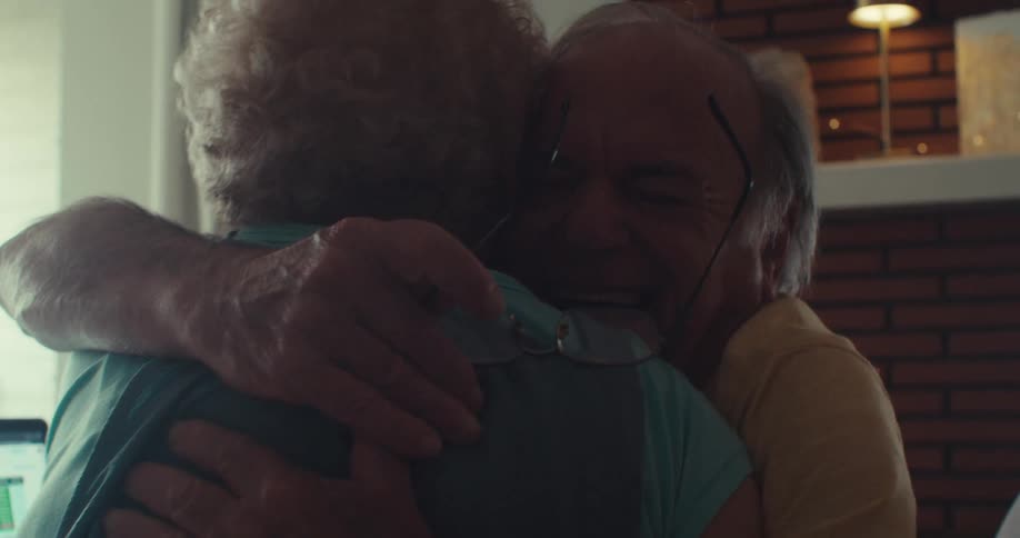 A man is talking and laughing then he hugs a woman