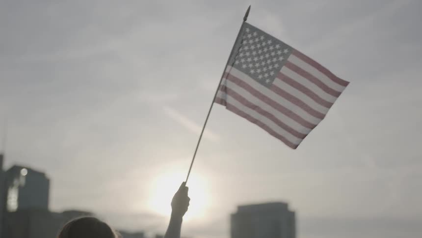 A woman is waving a flag in the cloudy sky