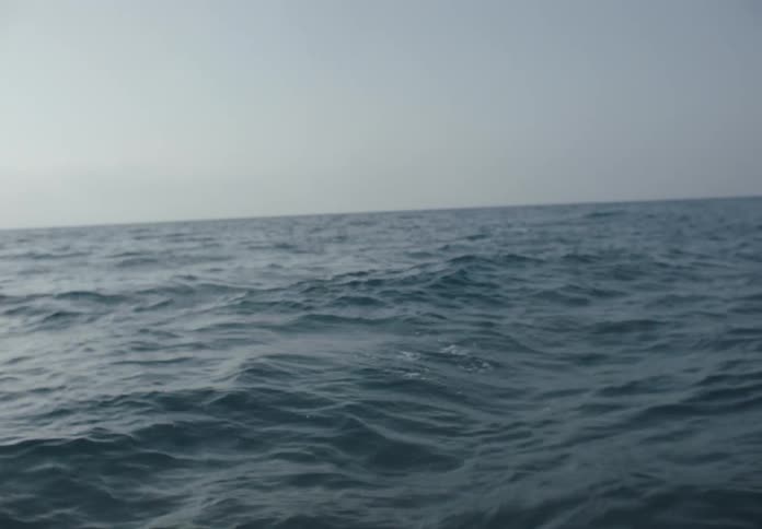 Child with life jacket swimming alone in ocean