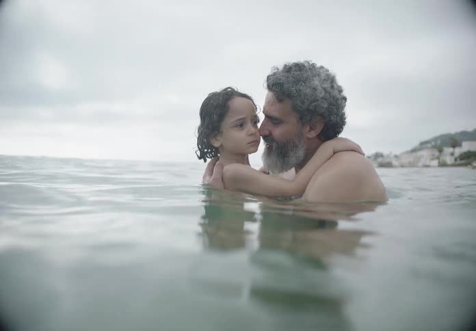 A father is holding his son in the water