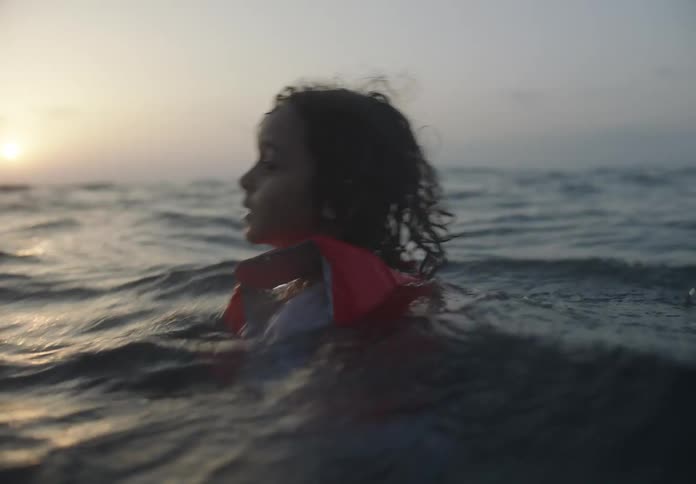 Child with life jacket swimming in the sea