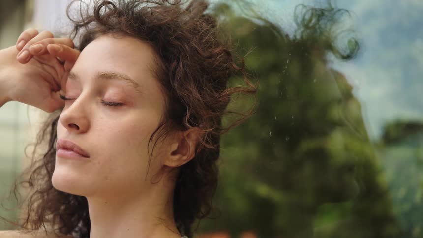 Woman with curly hair running her hand over her face
